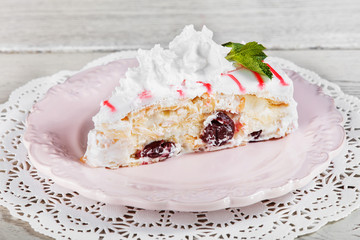 Tasty Cake with cream mascarpone and cherries on plate, on a light wooden background. Selective focus