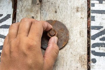 hand man install rusty nut and bolt on wood