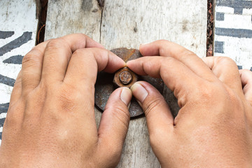 hand man install rusty nut and bolt on wood