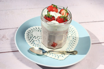 Fresh strawberries with fruit yoghurt and whipped cream on light pink wooden table