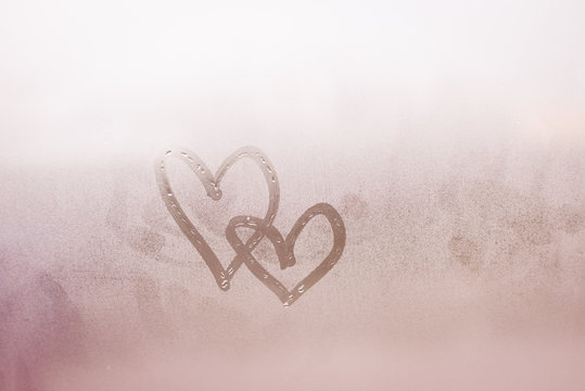 Love hearts painted on glass. The window is fogged 