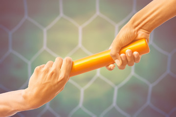 hands passing a relay baton on on soccer goal net background with vintage color tone effect.