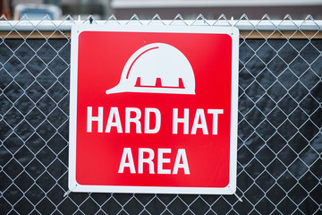 Hard hat area sign on chain link fence background 