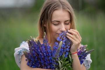 Portrait of beautiful young woman with flowers in the field