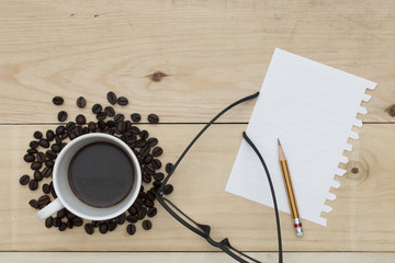 coffee, notebook, pencil and glasses on wood table