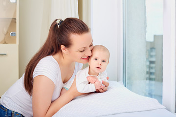 Mother holding sweet baby girl  near the window.