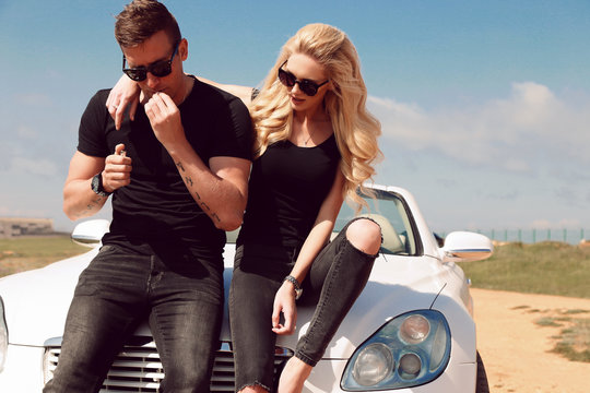 love story. fashion outdoor photo of impassioned couple in casual clothes, posing beside luxurious car  