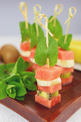 Sandwich of watermelon, kiwi and banana with a mint leaf.