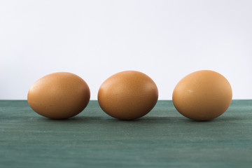 Three brown chicken eggs in a row, minimalist still life with eggs.