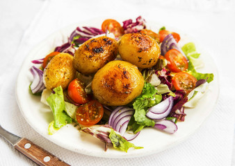 Roasted potatoes with vegetables salad on white plate