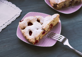 Piece of strawberry cake on lilac plate on wooden grey background