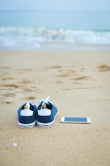 Closeup on smartphone on the beach. Top view flat lay style