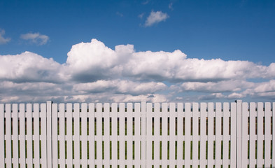 A white fence blocking a blue sky