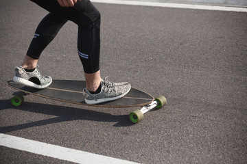 Fototapeta premium Man riding on longboard on road. Fitness or sport man resting and relaxing outdoors. Action shot of alongboarder skating on urban road.