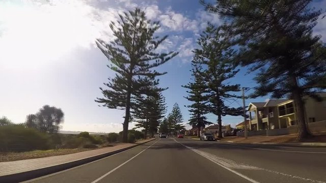 Driving along The Esplanade, Semaphore, Adelaide, South Australia, vehicle POV with afternoon sun and lens flare.