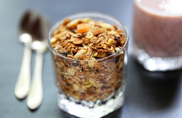 Granolai is for the breakfast in the transparent glass with yogurt, napkins and spoons on the grey background