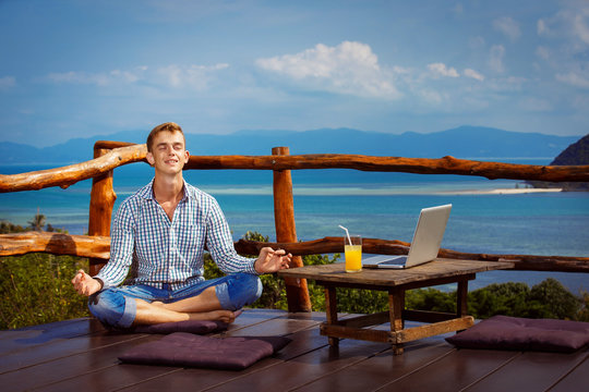 Young man  is sitting with closed eyes in yoga pose