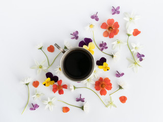 Overhead view cup of black coffee and colourful flowers on white background. Flat lay