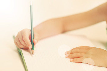 Children hand with pencil writing on notebook
