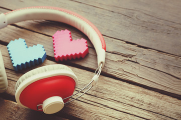 Red headphones near hearts on wooden background