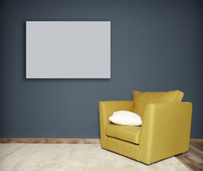 Green armchair and empty picture frame on grey wall background