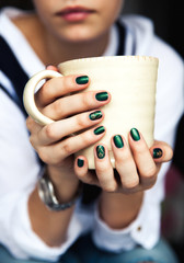 Stylish fashionable girl with a Cup of coffee and a green manicure in jeans. Fashion, care, beauty