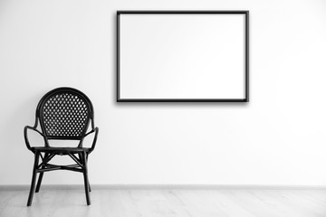 Black chair and empty picture frame on wall background