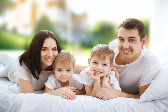 Happy family lying in bed on blurred background