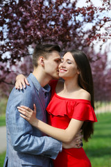 Fototapeta premium Romantic couple embracing outdoors under blooming trees, affectionate moment in spring park, love and relationship