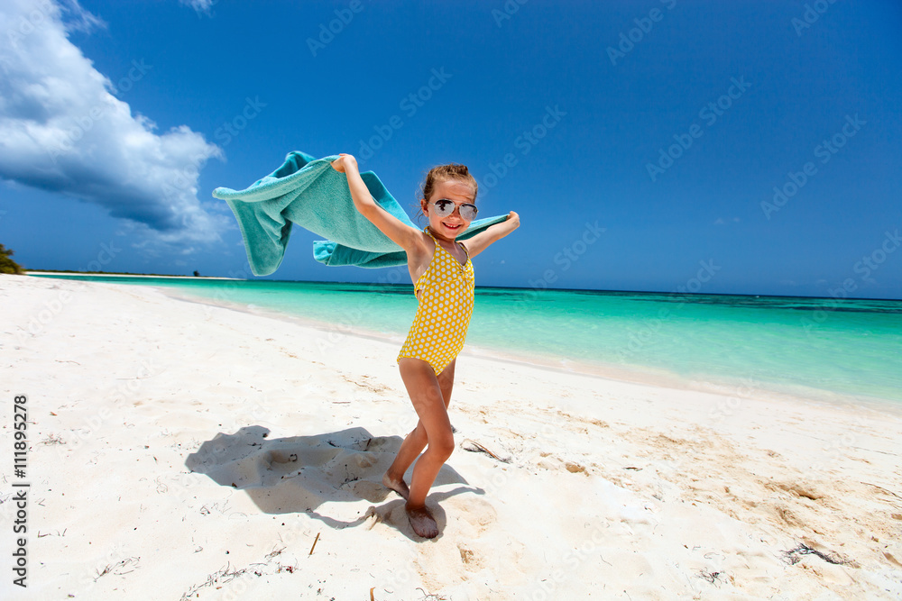 Wall mural cute little girl having fun on beach vacation