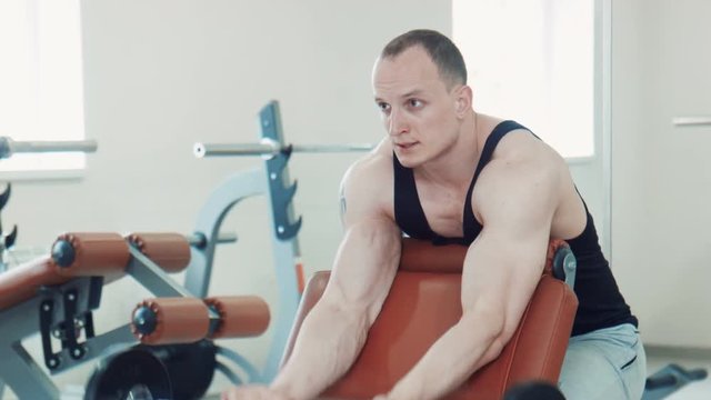 Bodybuilder doing scott curls with barbell
