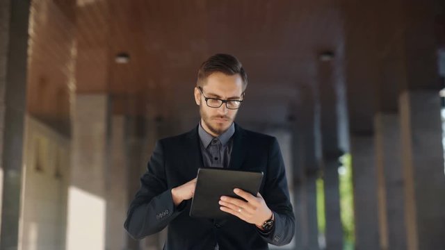 Young bearded businessman writting business e-mail using his tablet pc
