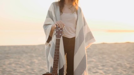 Beautiful young woman playing guitar on beach