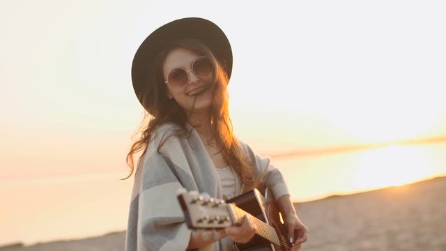slow motion. beautiful girl playing the guitar in a wheat field