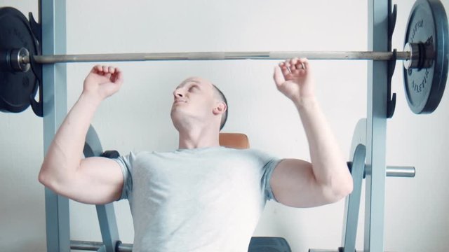 Bodybuilder doing scott curls with barbell