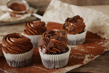 Chocolate cupcakes on baker paper over wooden background