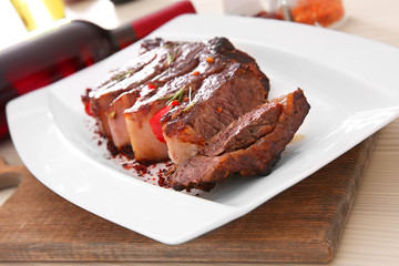 Sliced roasted pork steak with bottle of red wine on white plate