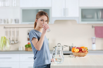 Young woman drinking water from glass in the kitchen