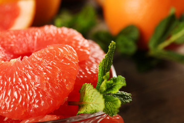 Juicy pieces of grapefruit with fresh mint on wooden table, close up