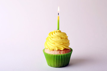 Birthday cupcake with candle on color background