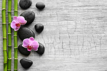 Spa stones, bamboo and orchids on wooden background