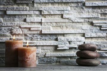 Composition of spa pebbles  and candles on grey brick wall background