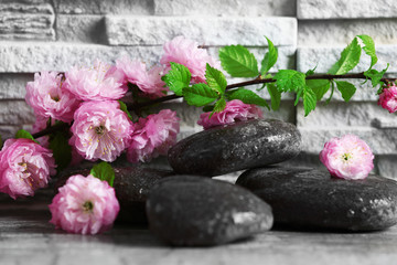 Composition of spa pebbles and beautiful flowers on grey brick wall background