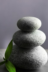 Composition of spa pebbles with bamboo leaf on grey wall background