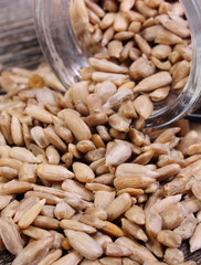 Sunflower seeds spilling out of glass jar. Wooden background