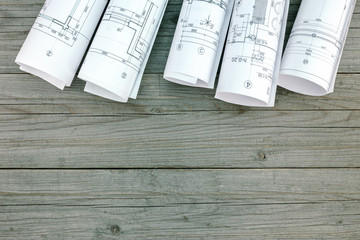 rolls of architectural blueprints and plans on gray wooden plank