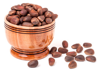 unpeeled cedar nuts in a wooden barrel on white background
