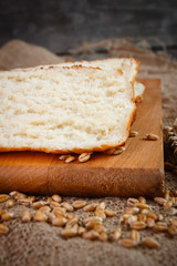 Fresh slices whole bread and wheat on the wooden board on burlap