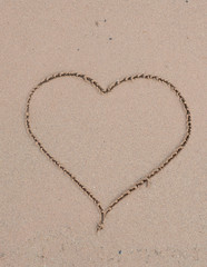 Fototapeta na wymiar Heart drawn in the sand. Beach background. vertical photo