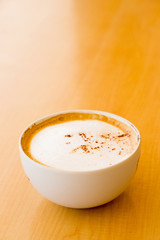 A cup of coffee in a white cup on wooden background